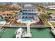 Aerial view of a backyard with a pool, spa, tropical landscaping, and a private boat dock at 440 Capri Blvd, Treasure Island, FL 33706