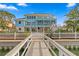 Stunning waterfront home showcasing multi-level balconies, lush landscaping, and a private dock with waterway access at 440 Capri Blvd, Treasure Island, FL 33706