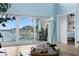 Living room showcasing large windows with water views, sliding glass doors to deck, and hardwood floors at 440 Capri Blvd, Treasure Island, FL 33706