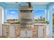 Well-equipped outdoor kitchen features a built-in grill, stone backsplash, granite countertops and cabinet storage at 440 Capri Blvd, Treasure Island, FL 33706