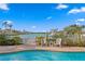 Waterfront view showcasing a pool, dock and lift with lush landscaping, lounge chairs and sunny skies at 440 Capri Blvd, Treasure Island, FL 33706
