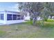Green backyard with a view of the home's sunroom, partially obscured by a mature bottlebrush tree at 4517 100Th N Ave, Pinellas Park, FL 33782