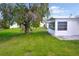 Lush backyard with a mature bottlebrush tree offering shade and a glimpse of the home's sunroom at 4517 100Th N Ave, Pinellas Park, FL 33782