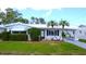 Charming single-story home with a white exterior, well-manicured lawn, and mature landscaping featuring palm trees at 4517 100Th N Ave, Pinellas Park, FL 33782
