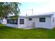 Backyard featuring a well-maintained green lawn and a sunroom attached to the rear of the house at 4517 100Th N Ave, Pinellas Park, FL 33782