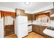 Bright kitchen with white appliances, wood cabinets, and a view of the entry door at 4814 Edmund Ct, Dover, FL 33527