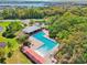 Aerial view of a community pool area with an amenity center, sunshades, seating, and a scenic backdrop at 5955 Sweet Birch Dr, Riverview, FL 33578