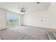 Bright living room with a ceiling fan, neutral carpet, and sliding glass doors with views of the pond at 5955 Sweet Birch Dr, Riverview, FL 33578