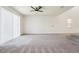 A spacious living room with plush carpeting, a ceiling fan, and a sliding glass door at 5955 Sweet Birch Dr, Riverview, FL 33578