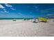 Picturesque beach scene with beach shades on the white sand shore and clear blue waters under a partly cloudy sky at 614 Gulf Blvd # 4, Indian Rocks Beach, FL 33785