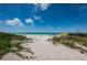 A sandy path leads to a scenic beach, with clear waters and a blue sky at 614 Gulf Blvd # 4, Indian Rocks Beach, FL 33785