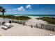 Outdoor patio features a picnic table and grill with a view of the sandy beach and clear blue sky at 614 Gulf Blvd # 4, Indian Rocks Beach, FL 33785