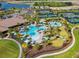 Aerial view of the community clubhouse with pools, tennis courts, manicured lawns and lush landscaping at 9708 Highland Park Pl, Palmetto, FL 34221