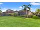 Spacious backyard with lush green lawn, mature trees, and a view of the screened-in lanai of the home at 9708 Highland Park Pl, Palmetto, FL 34221