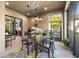 Covered patio featuring a glass table, grill, and views of the lush backyard and direct access to the kitchen at 9708 Highland Park Pl, Palmetto, FL 34221