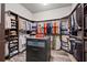 Large walk-in closet with custom shelving, dark wood cabinets and an island with drawers at 9708 Highland Park Pl, Palmetto, FL 34221