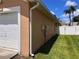 Attached one-car garage with a white door, siding and green yard on a sunny day at 10102 Cedar Dune Dr, Tampa, FL 33624