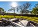 Outdoor lounge chairs on a brick patio overlooking the lush green lawn and mature trees at 12808 Harborwood Dr, Largo, FL 33774