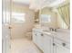 Bathroom with white cabinets, white tile floors, and a mirror with vanity lighting at 12808 Harborwood Dr, Largo, FL 33774
