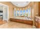 A luxurious bathtub with a view of the outdoors and custom window covering in this primary bathroom at 12808 Harborwood Dr, Largo, FL 33774
