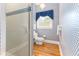 Bright bathroom with stylish wallpaper, glass shower, and hardwood floors at 12808 Harborwood Dr, Largo, FL 33774
