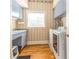 Laundry room with wood floors, blue cabinets, patterned wallpaper and washer/dryer at 12808 Harborwood Dr, Largo, FL 33774
