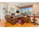 Cozy living room with leather furniture, a fireplace, built-in shelving, and a large window at 12808 Harborwood Dr, Largo, FL 33774