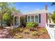 Charming pink house with lush landscaping and a walkway with a white picket fence at 1874 N Washington Ave, Clearwater, FL 33755