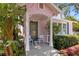 Inviting porch of a pink cottage with seating, a blue door, and decorative details at 1874 N Washington Ave, Clearwater, FL 33755