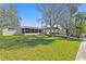 Spacious backyard featuring a screened-in patio, outdoor dining, lush lawn, mature trees, and easy access to the waterfront at 222 Mar St, St Pete Beach, FL 33706