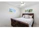 Cozy bedroom with white walls, wood-textured bed frame, neutral bedding, ceiling fan, and natural light from the windows at 222 Mar St, St Pete Beach, FL 33706