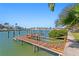 Waterfront home featuring a private wooden dock, boat lift, and lush greenery surrounding the area at 222 Mar St, St Pete Beach, FL 33706