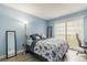 Bright blue bedroom with a large window, tiled floors, a full-size mirror, and a comfortable bed at 2625 State Road 590 # 2612, Clearwater, FL 33759