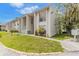 White townhouse with a green lawn, short sidewalk, and trees, under a blue sky with white clouds at 2625 State Road 590 # 2612, Clearwater, FL 33759