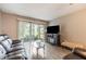 Living room with wood tile flooring, leather sofas, sliding glass doors to lanai, and a vintage entertainment center at 2625 State Road 590 # 2612, Clearwater, FL 33759