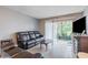 Living room with wood tile flooring, leather sofas, sliding glass doors to lanai, and a vintage entertainment center at 2625 State Road 590 # 2612, Clearwater, FL 33759
