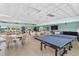 Bright game room with ping pong table, chairs, tables, and a waterfront view through large windows for an active lifestyle at 31 Island Way # 106, Clearwater Beach, FL 33767