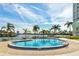 Community pool overlooking a lake with palm trees and lounge chairs at 31 Island Way # 106, Clearwater Beach, FL 33767