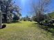 Wide shot of the huge backyard with a partial fence and mature trees, offering ample space and privacy at 37324 Rose Ave, Dade City, FL 33523