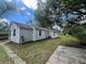 Low angle of light grey single story home with blue skies and mature landscaping at 37324 Rose Ave, Dade City, FL 33523