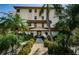 Exterior view of a condo building entrance with well-manicured landscaping and a welcoming pathway at 479 E Shore Dr # 8, Clearwater, FL 33767