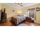 Neutral bedroom with hardwood floors featuring a ceiling fan, a window with blinds, and simple furnishings at 7440 Mint Julep Dr, Riverview, FL 33578