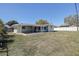 Backyard featuring a grassy lawn, covered patio area, and a white privacy fence at 10915 Hammock Dr, Largo, FL 33774