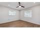 Cozy bedroom with two windows, wood-look flooring, and a ceiling fan at 10915 Hammock Dr, Largo, FL 33774