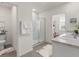 Well-lit bathroom with dual sinks, white cabinets, a walk-in shower, and neutral-colored tile flooring at 11617 Miracle Mile Dr, Riverview, FL 33578