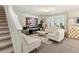 Bright living room with white sofas, a large TV, and modern decor, accented by a staircase at 11617 Miracle Mile Dr, Riverview, FL 33578
