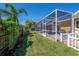 A vibrant backyard features a screened pool enclosure, lush lawn, and well-maintained landscaping for outdoor living at 12406 Bristol Commons Cir, Tampa, FL 33626