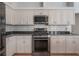 Stylish kitchen featuring stainless steel oven and microwave, white cabinets, and dark granite countertops at 12406 Bristol Commons Cir, Tampa, FL 33626
