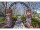 The brick archway leads into a serene walking path with mature trees and lush landscaping on either side at 12406 Bristol Commons Cir, Tampa, FL 33626