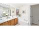 Bright bathroom featuring dual sinks, a large tub, natural light, with neutral tile, and white cabinetry at 12705 Longcrest Dr, Riverview, FL 33579